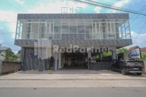 um edifício com um carro estacionado em frente em Garuda Guesthouse Yogyakarta RedPartner em Yogyakarta