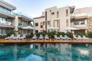 a swimming pool with chairs and umbrellas in front of buildings at Brand new, Beachfront Ocean Terraces, Poste Lafayette-Apt-C4 in Poste Lafayette