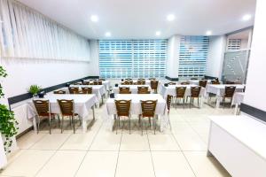 a restaurant with white tables and chairs and windows at Diera Family Hotel in Atakum