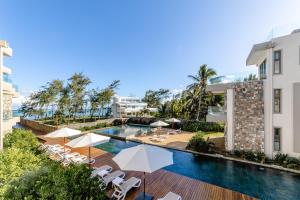 a swimming pool with chairs and umbrellas next to a building at Brand new, Beachfront Ocean Terraces, Poste Lafayette-Apt-C4 in Poste Lafayette