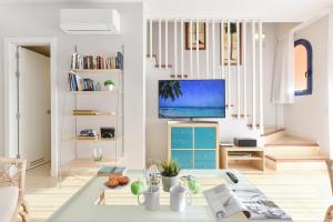 a living room with a table and a tv at Duplex Bahia Meloneras 47 by VillaGranCanaria in Meloneras