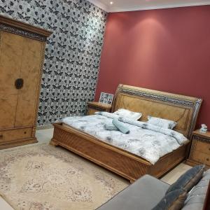 een slaapkamer met een bed en een rode muur bij العين الهيلي مصباح بيت14 in Al Ain