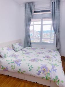 a bed in a room with a window and a bedspread with flowers at Horizon Homestay in Ấp Kim Thạch