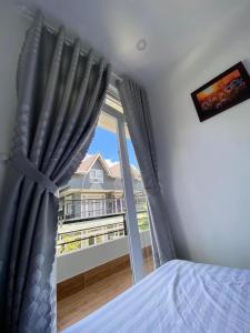 a bedroom with a window with a view of a house at Horizon Homestay in Ấp Kim Thạch