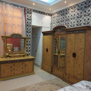 een slaapkamer met een houten kast en een spiegel bij العين الهيلي مصباح بيت14 in Al Ain