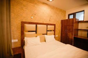 Schlafzimmer mit einem Bett mit weißer Bettwäsche und Kissen in der Unterkunft Seven Hills Resort Srinagar By Him Haults Hospitality in Srinagar