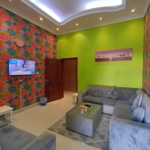 een woonkamer met een bank en een groene muur bij العين الهيلي مصباح بيت14 in Al Ain