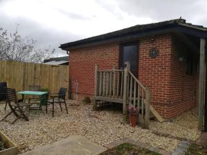 a patio with a bench and a table and a building at The Lodge, countryside living in Churchdown
