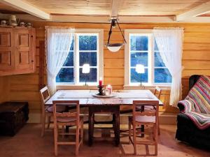 una sala da pranzo con tavolo e sedie e due finestre di Holiday home Grimstad a Grimstad