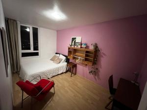 a bedroom with pink walls and a bed and a red chair at ARTHOUSE Room Paris entre Disneyland Paris in Neuilly-sur-Marne