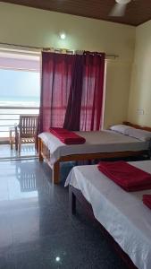 a room with two beds and a chair and a window at Gokarna Govekar Sea Facing Rooms in Gokarn