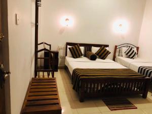 a bedroom with two beds and a chair in it at Shadow Inn Guest House in Ella