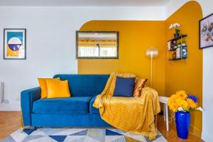 a blue couch in a living room with yellow walls at Artémis-10 min. from Versailles Gardens, parking in Le Chesnay