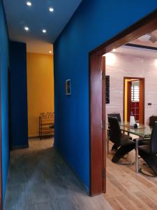 Habitación con pared azul, mesa y sillas en Magnifique appartement, en Cotonou