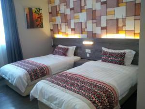 two beds in a hotel room with a mosaic wall at Ajang Hotel in Miri