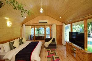 a bedroom with a bed and a tv in a room at Tree house Latos Tandi in Jibhi +29 photos
