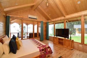 a large room with a bed and a flat screen tv at Tree house Latos Tandi in Jibhi