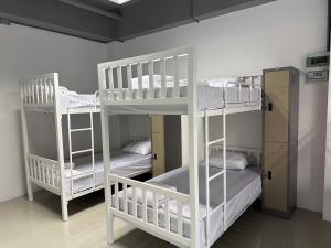 2 witte stapelbedden in een kamer bij PJ Hostel in Pak Chong