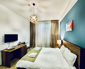 a bedroom with a large bed and a tv at Hotel King Tom in Tbilisi City