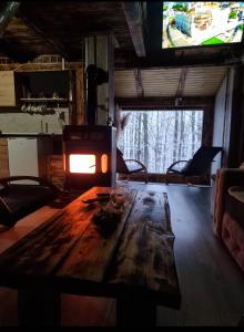 sala de estar con mesa de madera y chimenea en Vikendica Kozara en Kozarac