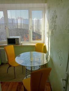 リヴィウにあるApartment on Historical Center of Lvivのダイニングルーム(ガラステーブル、黄色の椅子付)