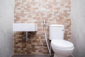 La salle de bains est pourvue de toilettes et d'un mur en briques. dans l'établissement Urbanview Syariah Loji Arum Stasiun Klaten by RedDoorz, à Klaten