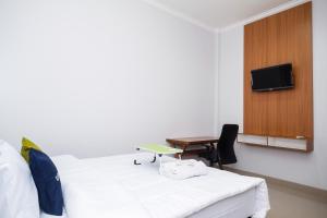 a room with a bed and a desk and a tv at Urbanview Syariah Loji Arum Stasiun Klaten by RedDoorz in Klaten