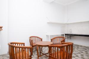 a kitchen with three chairs and a wooden table at Urbanview Syariah Loji Arum Stasiun Klaten by RedDoorz in Klaten
