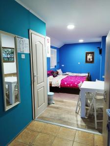 um quarto azul com uma cama, uma mesa e uma porta em Soba Milica em Palić