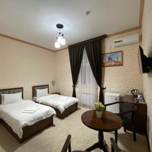 una camera d'albergo con due letti e un tavolo di HOTEL ALMAZ PLAZA a Yakkasaray Altre 51 foto