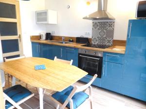 een keuken met een houten tafel en blauwe kasten bij La villa plein vent "La Bounty" gite 50m de la plage in Barneville-Carteret