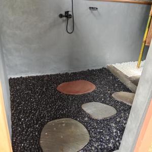 a bathroom with a shower with stepping stones on the floor at Bali jungle cabin in Jatiluwih