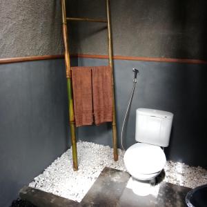 a bathroom with a toilet and a towel at Bali jungle cabin in Jatiluwih