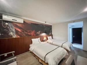 twee bedden in een kamer met een schilderij aan de muur bij Tianshui Times Hotel Zhangjiagang in Zhangjiagang