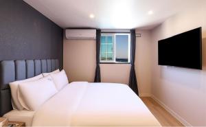 a bedroom with a bed and a flat screen tv at Hotel Daon in Pohang