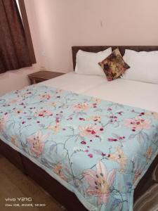 a bed with a blue blanket with flowers on it at Hotel vikram in Khajurāho