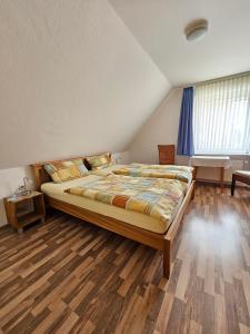 ein Schlafzimmer mit einem großen Bett und Holzböden in der Unterkunft Ferienhaus Wellsandt in Norderney