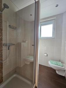 uma casa de banho com um chuveiro, um WC e um lavatório. em Ferienhaus Wellsandt em Norderney