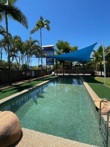 a swimming pool in a resort with palm trees at Kookaburra Holiday Park in Cardwell