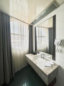 a bathroom with a sink and a large mirror at Tianshui Times Hotel Zhangjiagang in Zhangjiagang