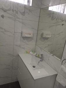 a white bathroom with a sink and a mirror at Big Valley Lakeside Paradise Motor Inn in Shepparton