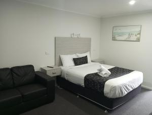 Habitación de hotel con cama y sofá en Big Valley Lakeside Paradise Motor Inn, en Shepparton