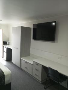 a hotel room with a desk and a tv on the wall at Big Valley Lakeside Paradise Motor Inn in Shepparton