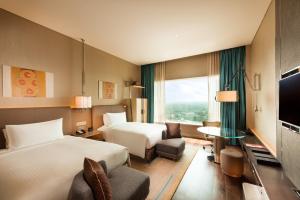 a hotel room with two beds and a television at Conrad Pune in Pune
