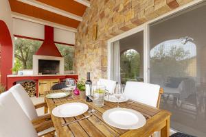 uma sala de jantar com uma mesa de madeira e cadeiras brancas em Red House Trget with Swimming Pool, Sauna and Jacuzzi em Labin