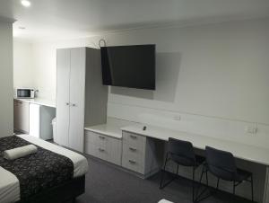 a hotel room with a bed and a desk with two chairs at Big Valley Lakeside Paradise Motor Inn in Shepparton