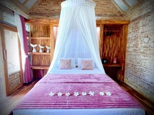 a bed with a canopy in a room at Purple Beach - Maïthélia - Gili Air in Gili Air