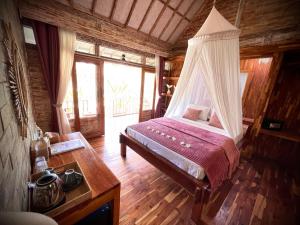 a bedroom with a bed with a mosquito net at Purple Beach - Maïthélia - Gili Air in Gili Air