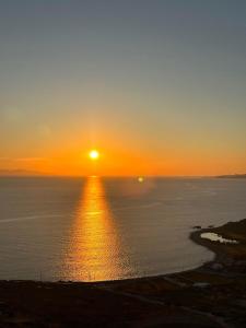 una puesta de sol sobre el océano con la puesta de sol en White Rock Suites & Villas, en Houlakia