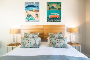 a bedroom with a bed with two lamps and two posters at Camps Bay Village in Cape Town